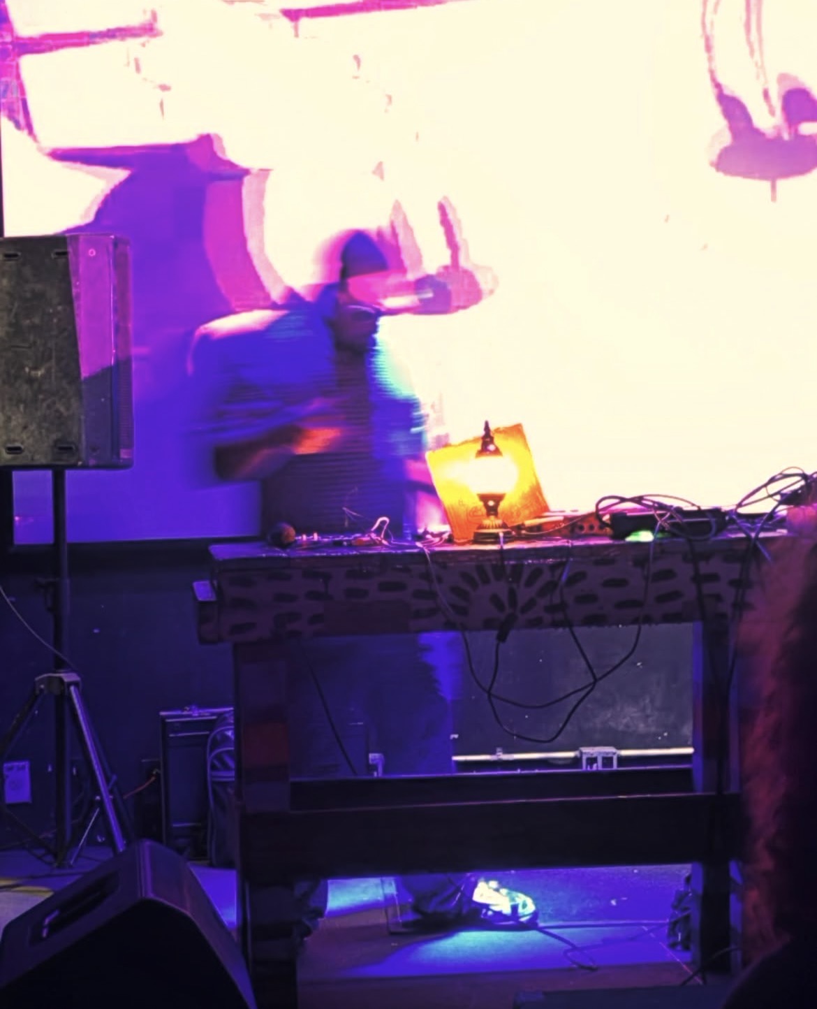 Live electronic music performance with colorful projections and equipment on stage