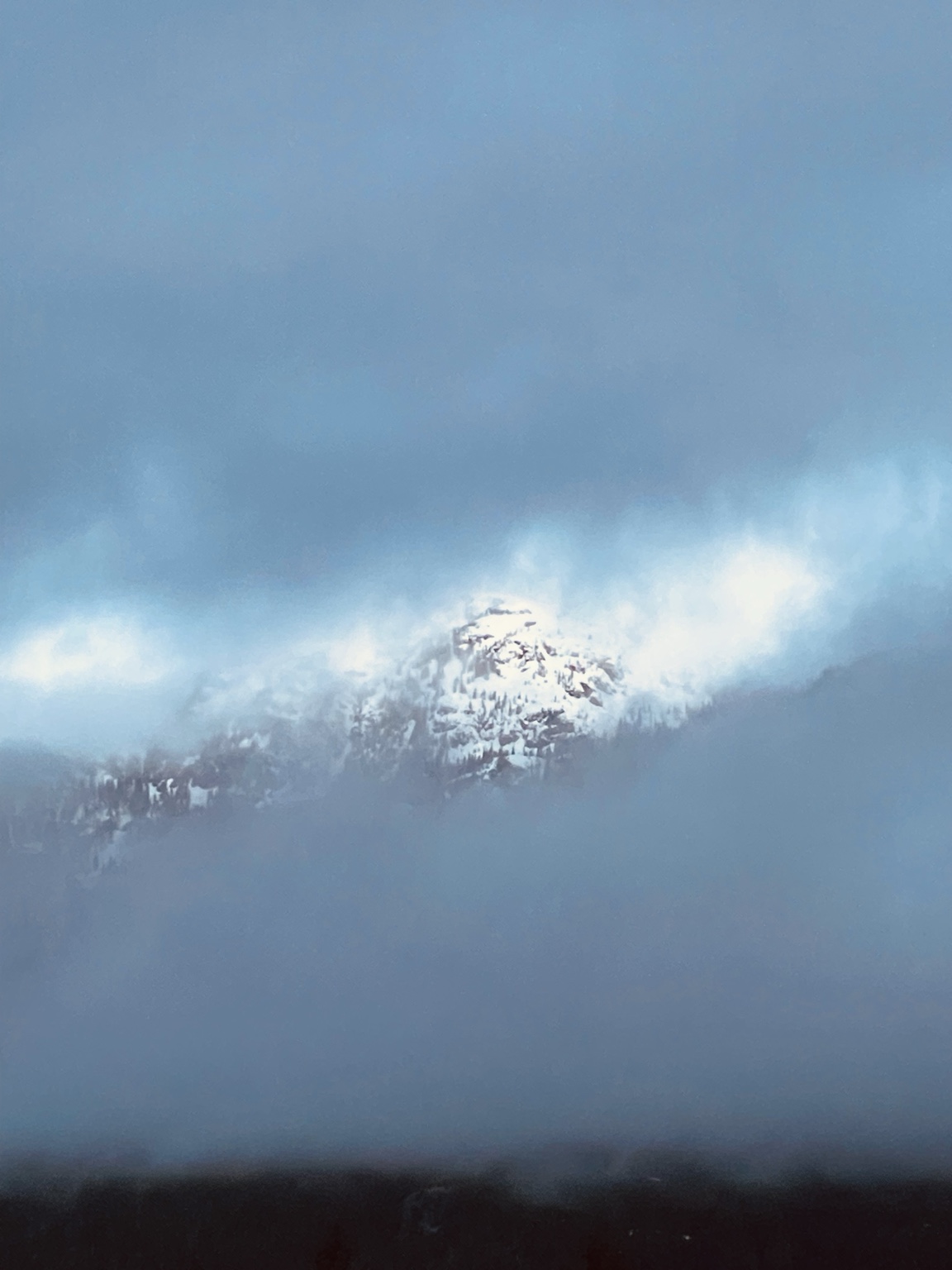 A snow-covered mountain emerging through blue clouds